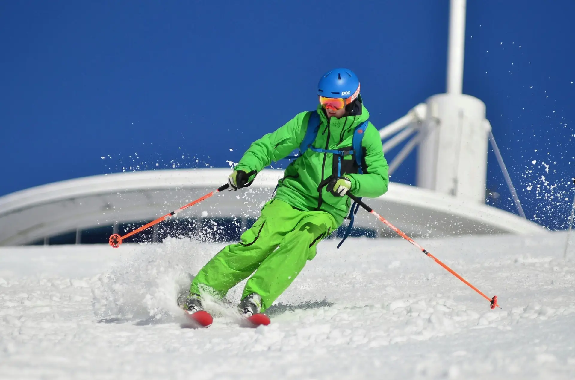 A skier in vibrant gear carves through fresh snow on a sunny winter day.